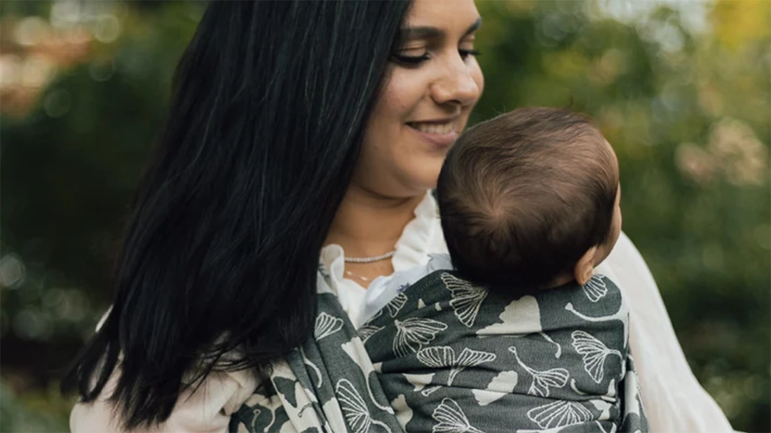 Une maman porte son nouveau-né en écharpe de portage tissée Chimparoo.